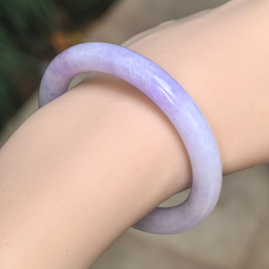 Angled wrist view of a glutinous lavender round-bar jadeite bangle showing its rounded profile and polished finish.