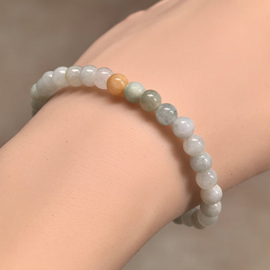 Angled wrist view of a pale green glutinous jadeite bead bracelet with a warm yellow accent bead.