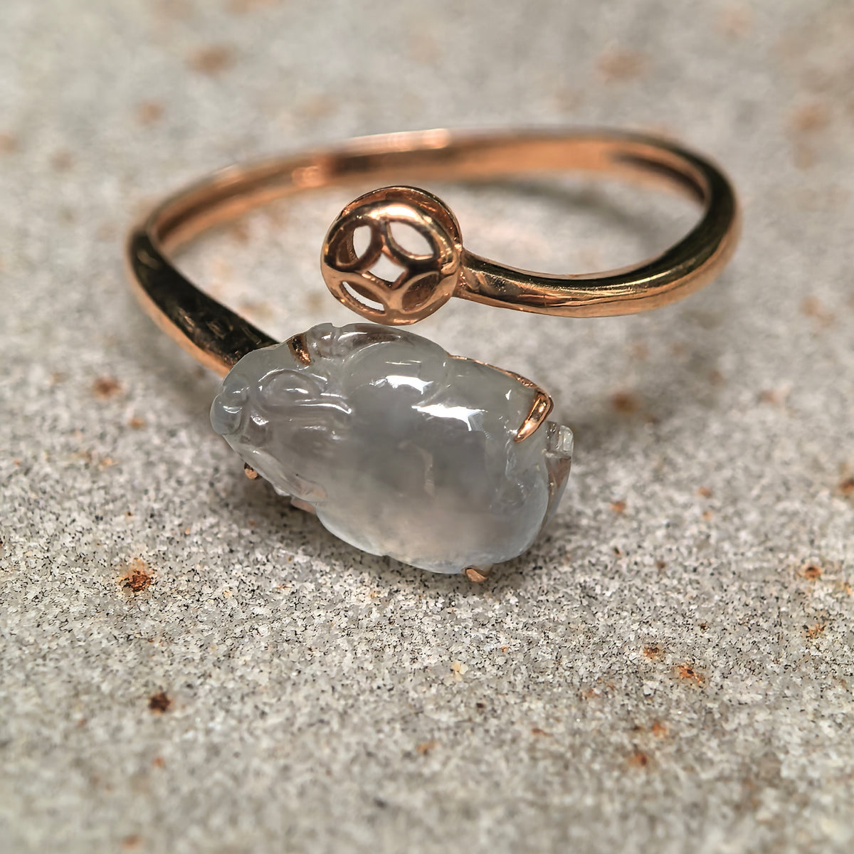 Close view of the white jadeite Pixiu ring on stone, highlighting the rounded carving and open 18K gold band.