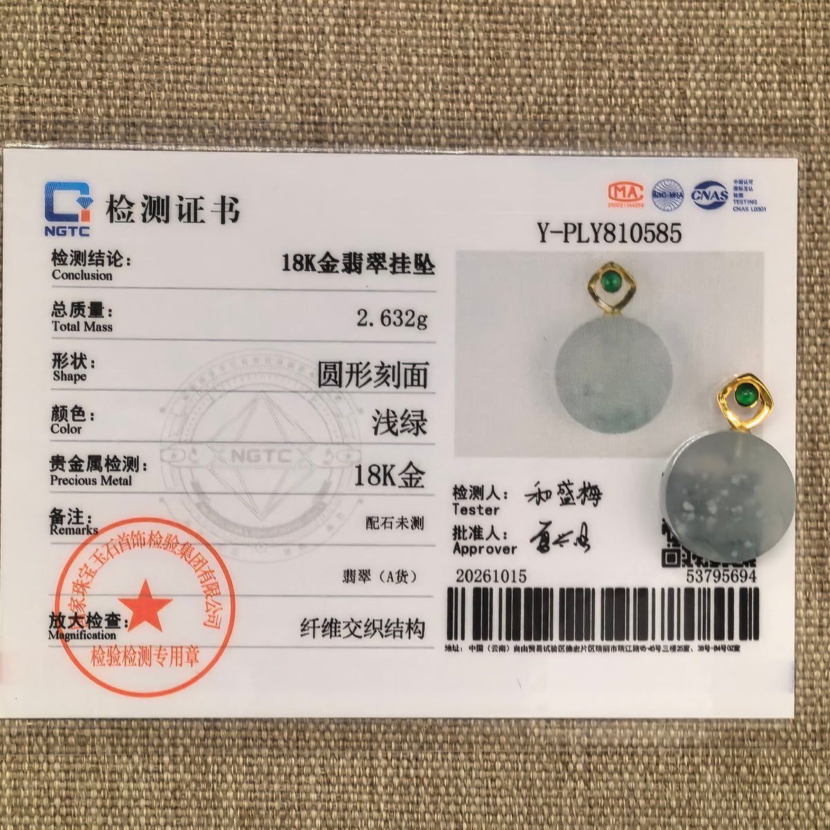White jadeite Plain Plaque Pendant with snowflake inclusions and an 18K gold bail beside its matching NGTC certificate on woven fabric.