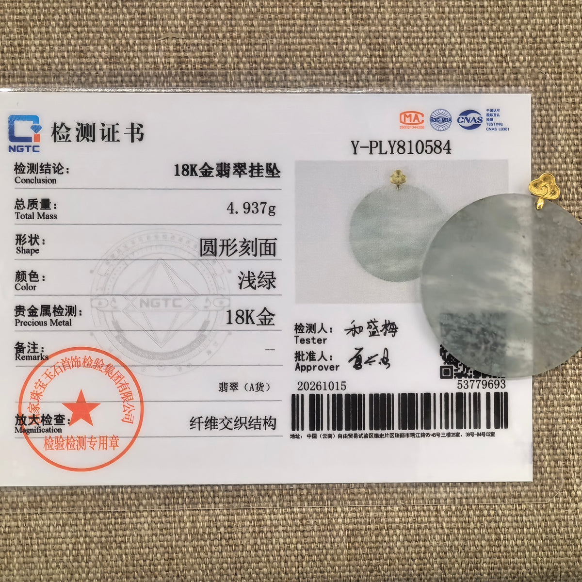Icy white jadeite Plain Plaque Pendant with snowflake inclusions and an 18K gold bail beside its matching NGTC certificate on woven fabric.