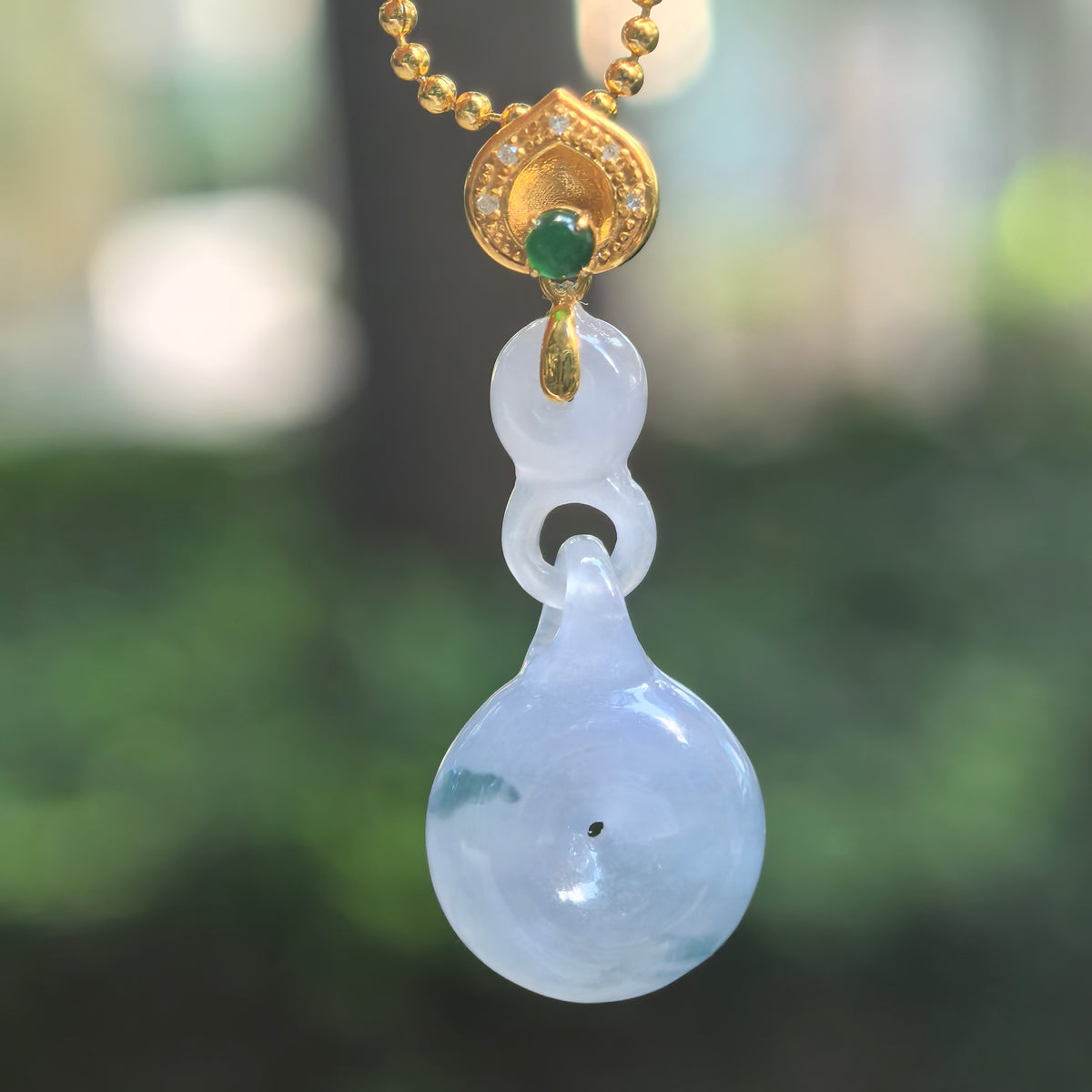 Icy purple jadeite Peace Pendant hanging from a chain, showing integral jadeite links, green patches, and an 18K gold bail with diamonds.