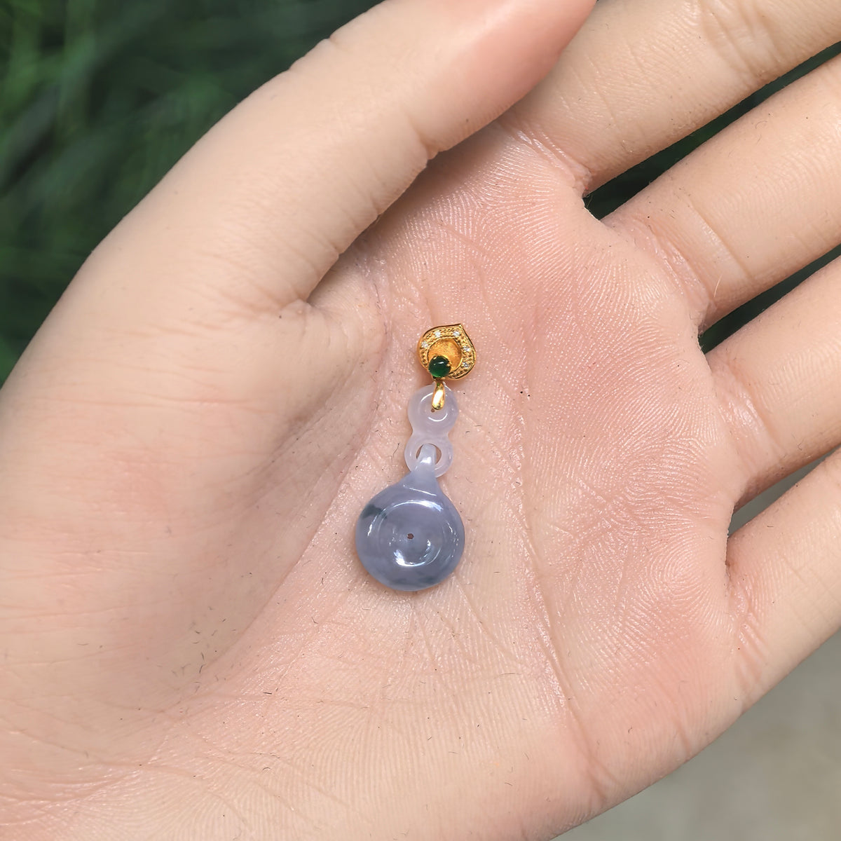 Purple jadeite Peace Pendant resting in an open palm, showing its proportions, interlocking carved links, and decorative gold bail.