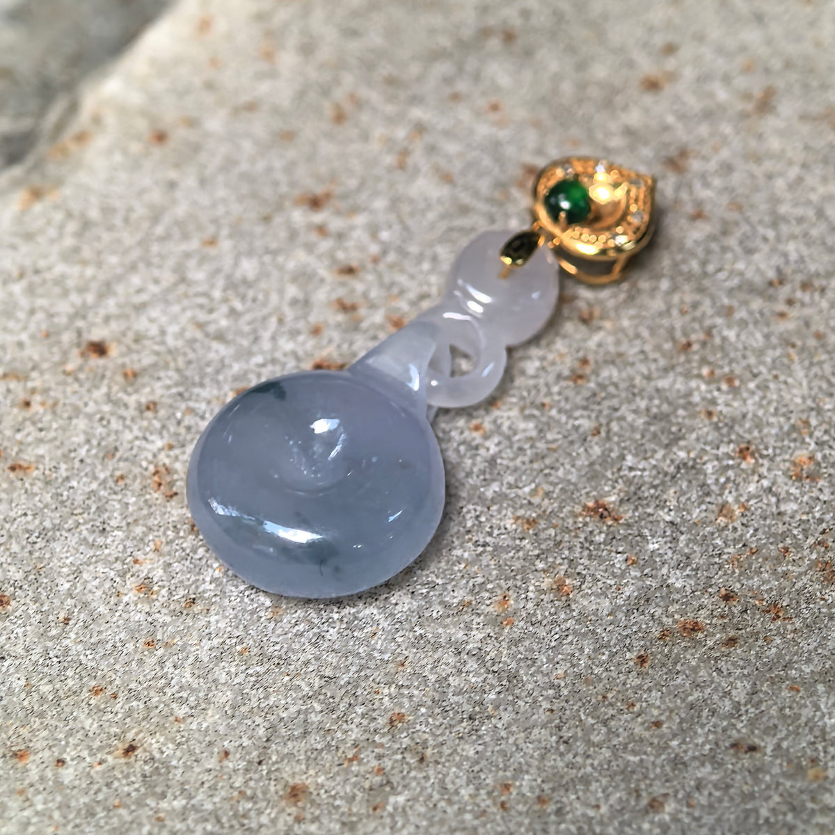 Angled view of the purple jadeite Peace Pendant on stone, showing its rounded disc, small central opening, and interlocking jadeite connection.