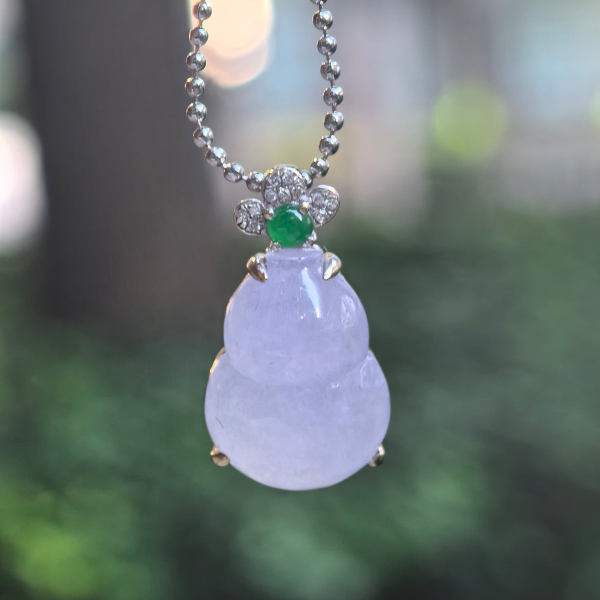 Icy purple jadeite Gourd Pendant hanging from a chain, showing its rounded silhouette and floral top with diamonds and a green accent stone.
