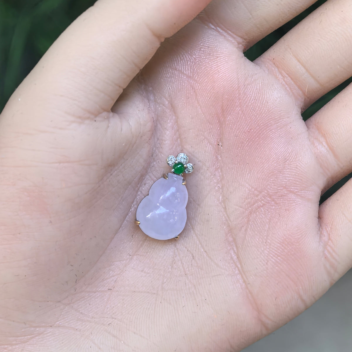 Purple jadeite Gourd Pendant resting in an open palm, showing its proportions, polished face, and 18K gold prong setting.