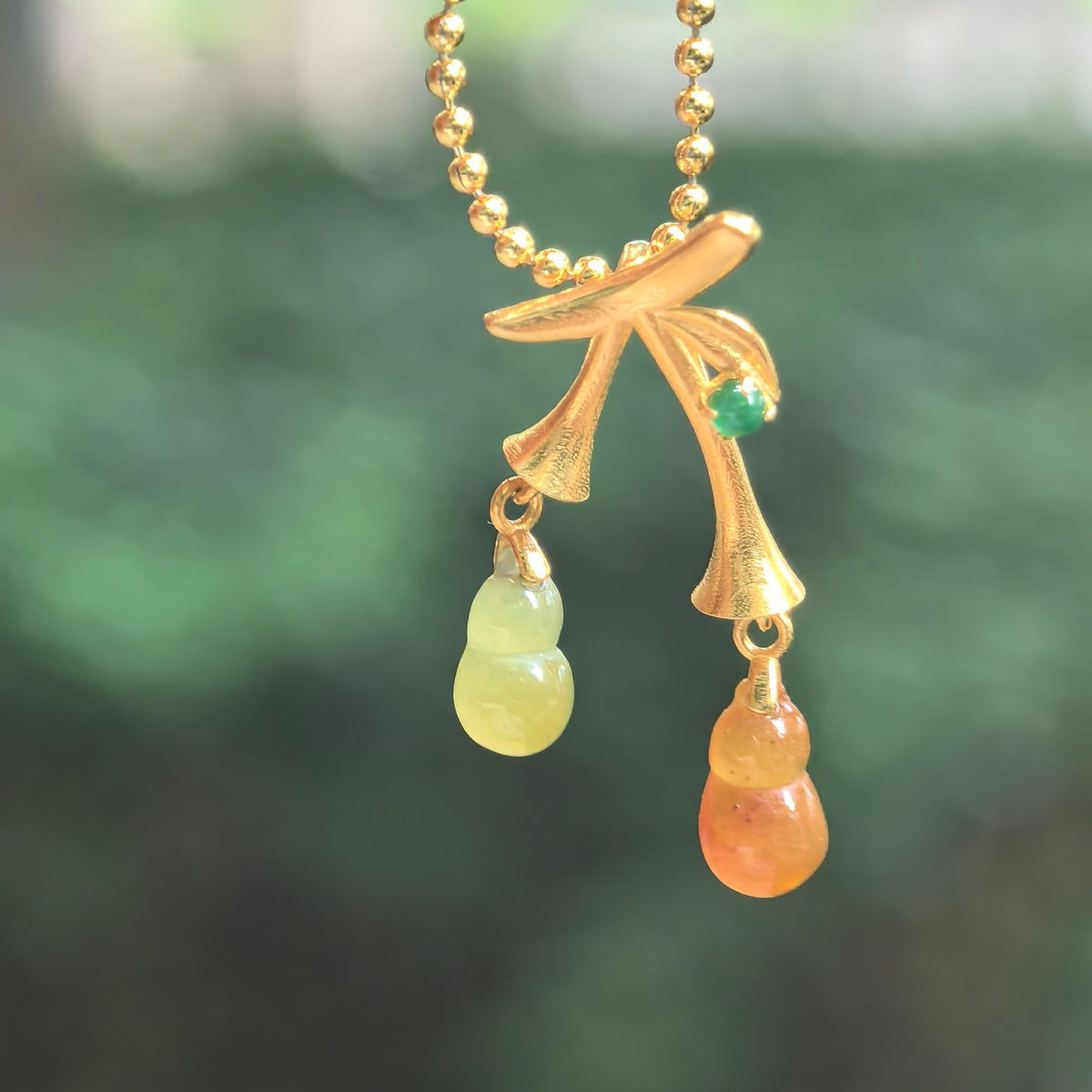 Icy red and yellow jadeite double Gourd Pendant hanging from a chain, with curved 18K gold stems, a leaf detail, and a green accent stone.