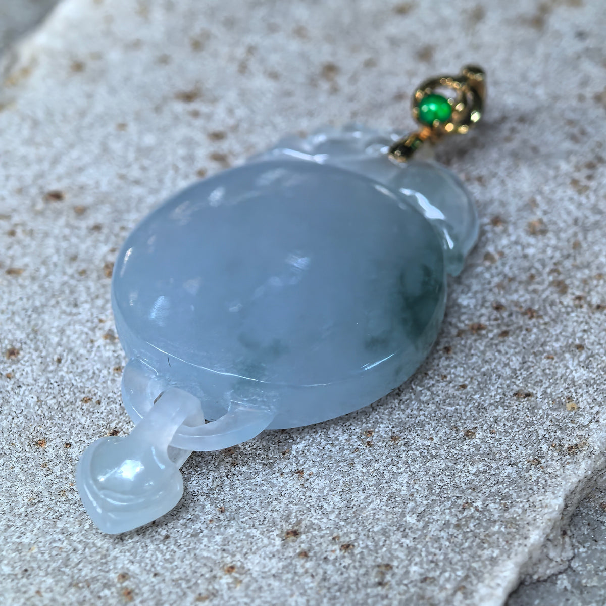 Angled close-up of the purple jadeite Plain Plaque Pendant on stone, showing its curved polished face, green accents, and heart linked through the lower loop.