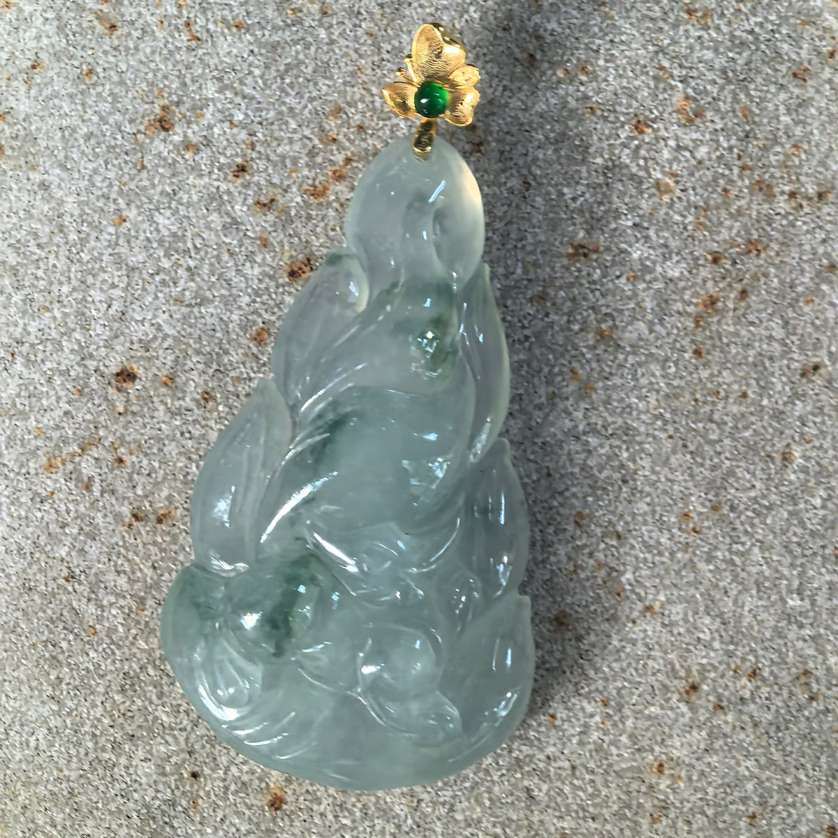Front view of the light green jadeite Nine-Tailed Fox Pendant on stone, showing sweeping tails, polished contours, and an 18K gold floral bail.