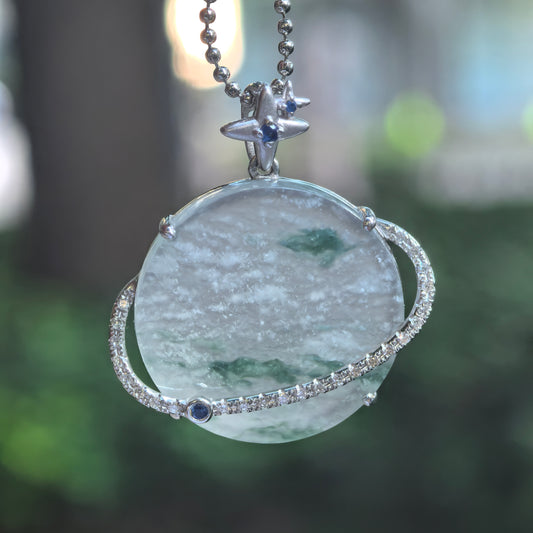 Hanging view of a pale green jadeite Planet Pendant, showing snowflake-like inclusions, green accents, a diamond-set orbital ring and crescent moon and star bail.