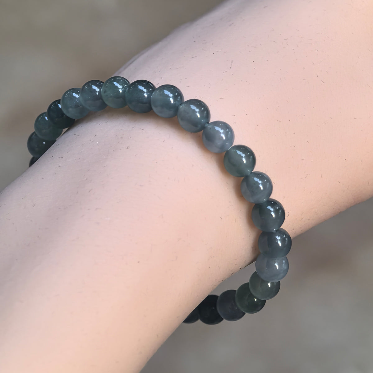 Deep green Guatemalan jadeite bead bracelet worn on the wrist at an angle, showing polished round beads and natural tonal variations.