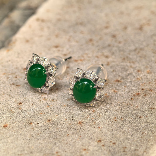 Angled view of the green jadeite stud earrings on stone, showing the domed cabochons, natural diamond halos and raised 18K gold settings.
